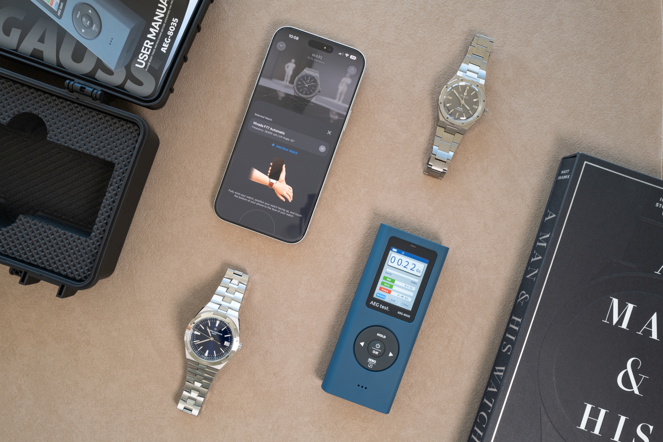 Test equipment layout: AEGTEST 8035 gaussmeter, iPhone with tickIQ app, mechanical watches, and carrying case