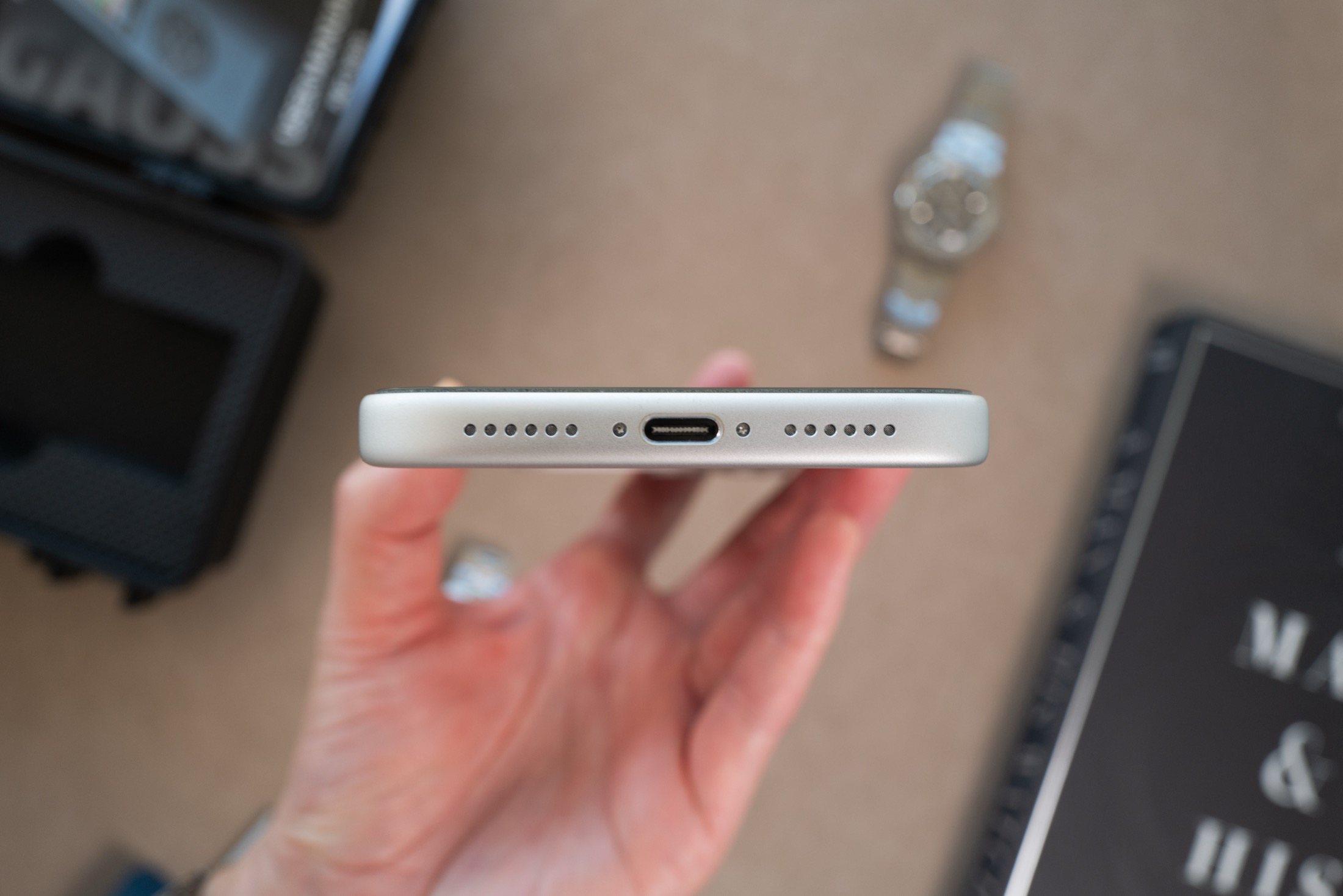 Close-up of iPhone bottom edge showing microphone, USB-C port, and speaker from left to right