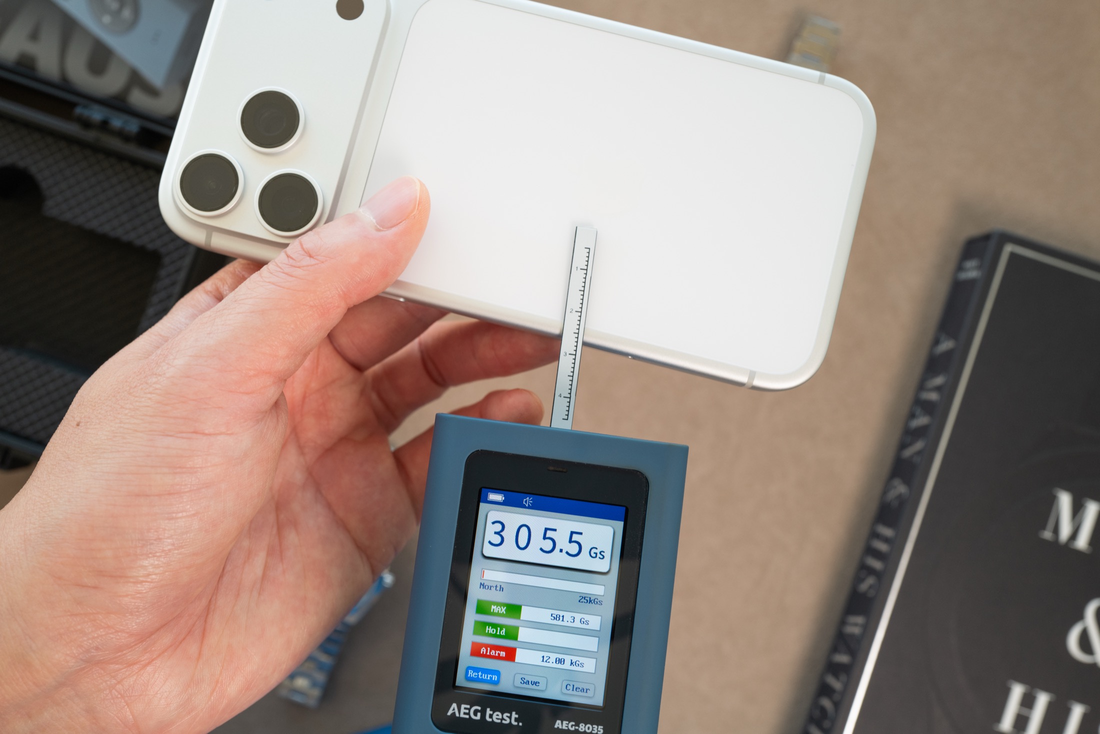 Gaussmeter probe measuring iPhone MagSafe ring, display showing 305.5 Gauss with max reading of 580 Gauss